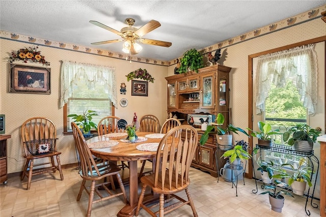 dining area with wallpapered walls, a ceiling fan, healthy amount of natural light, baseboards, and a textured ceiling