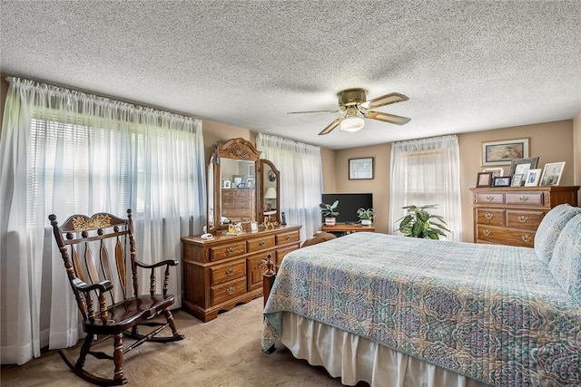 bedroom featuring light carpet, ceiling fan, and a textured ceiling