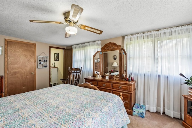 bedroom featuring a textured ceiling, light carpet, and a ceiling fan