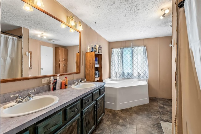 full bath with a textured ceiling, a bath, and double vanity