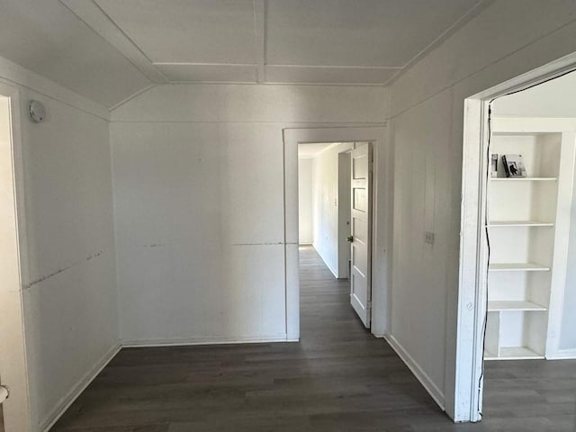 hallway with dark wood-style flooring, vaulted ceiling, and baseboards