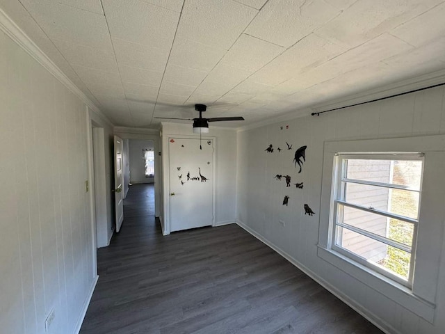 interior space featuring ornamental molding, dark wood-type flooring, ceiling fan, and baseboards