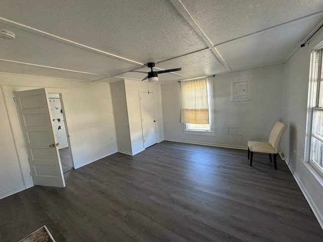 unfurnished room with dark wood-type flooring, a textured ceiling, baseboards, and plenty of natural light