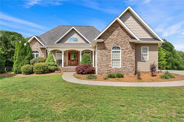 craftsman-style house featuring stone siding, a front lawn, and covered porch