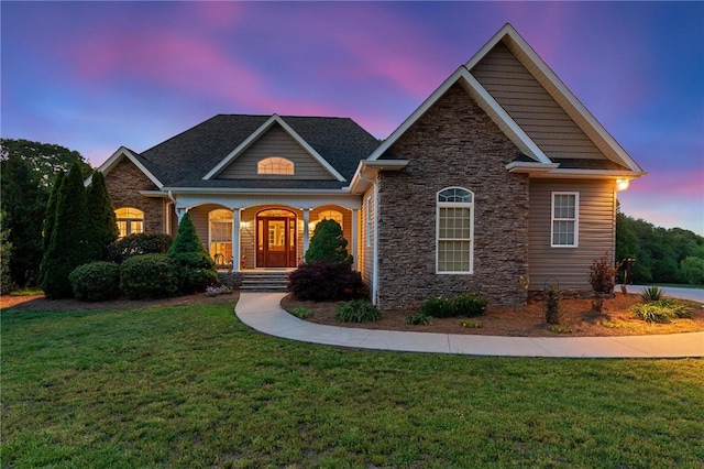 craftsman house with stone siding, a lawn, and covered porch