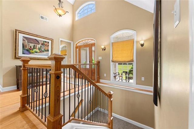 staircase featuring baseboards, high vaulted ceiling, and wood finished floors