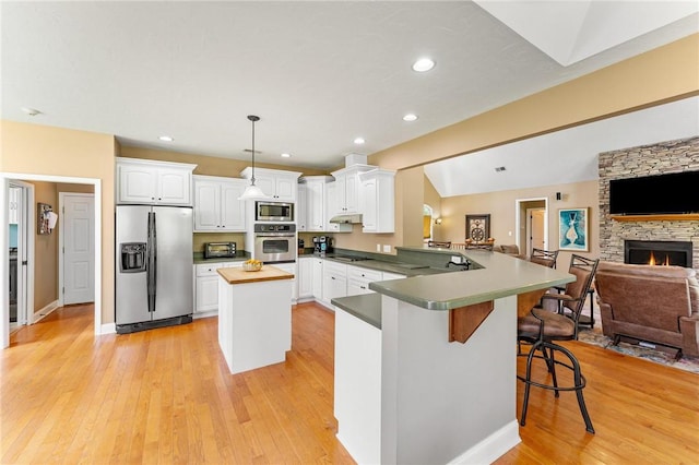 kitchen featuring appliances with stainless steel finishes, open floor plan, white cabinetry, a peninsula, and recessed lighting