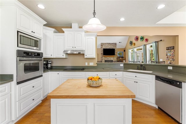 kitchen with stainless steel appliances, a sink, butcher block countertops, white cabinets, and light wood finished floors