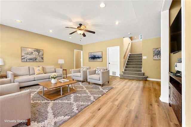 living room featuring baseboards, stairs, ceiling fan, wood finished floors, and recessed lighting