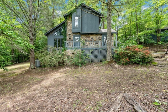 rear view of house with a wooden deck and stone siding