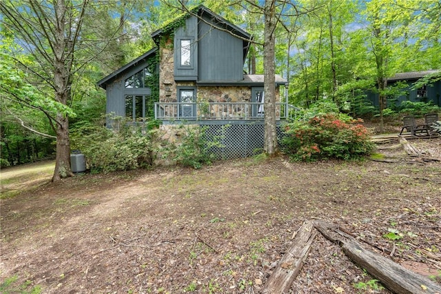 back of house with stone siding and a deck