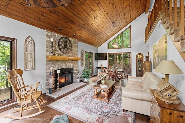 living room with wood ceiling, wood finished floors, high vaulted ceiling, a stone fireplace, and stairs