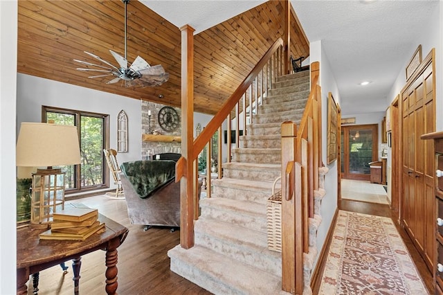 staircase with a fireplace, ceiling fan, wood finished floors, recessed lighting, and vaulted ceiling