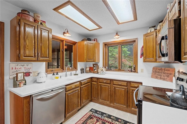 kitchen with stainless steel appliances, a sink, brown cabinets, and a textured ceiling