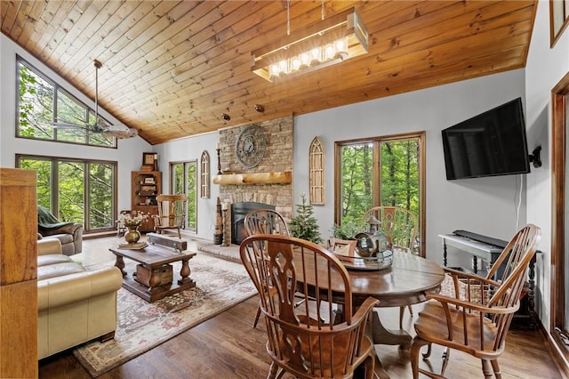 dining space with wood ceiling, a fireplace, wood finished floors, plenty of natural light, and high vaulted ceiling
