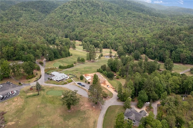 aerial view of property and surrounding area featuring a heavily wooded area and a mountainous background
