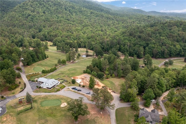 view of property location with a forest, mountains, and a golf course