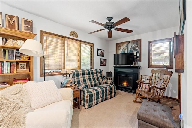 living room with carpet, ceiling fan, and a glass covered fireplace