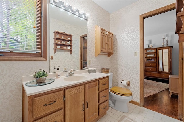bathroom featuring wallpapered walls, toilet, vanity, and tile patterned floors