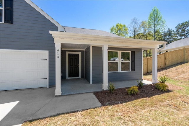 view of exterior entry featuring fence and covered porch