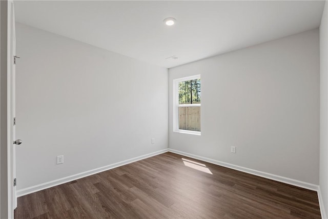 empty room with dark wood-style flooring and baseboards
