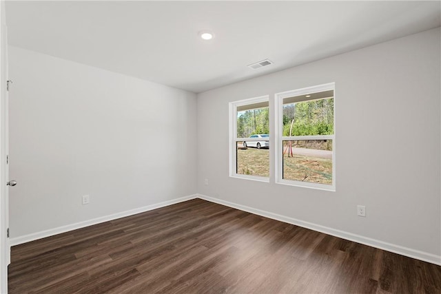 spare room featuring dark wood-type flooring, baseboards, and recessed lighting