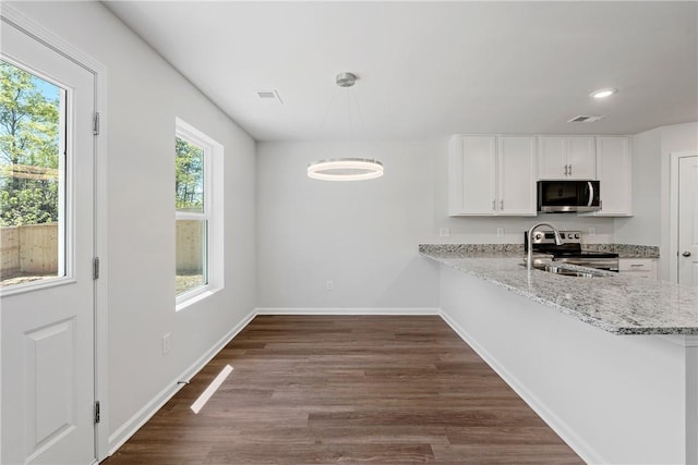 kitchen with stainless steel appliances, white cabinets, a sink, dark wood finished floors, and light stone counters