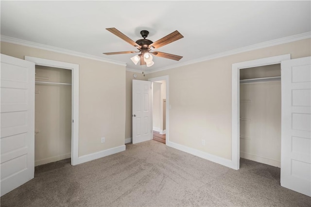unfurnished bedroom with ornamental molding, carpet floors, baseboards, two closets, and ceiling fan