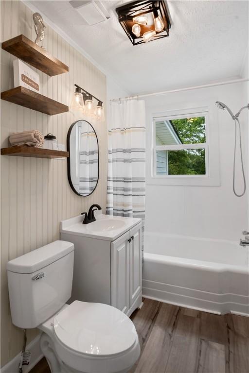 full bathroom featuring wood finished floors, toilet, shower / bath combo, crown molding, and vanity