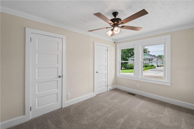 unfurnished bedroom featuring baseboards, carpet floors, crown molding, ceiling fan, and a textured ceiling