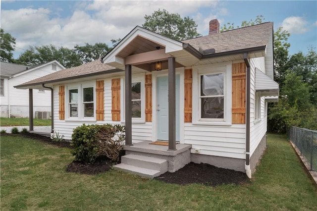 view of front of house featuring a chimney, a shingled roof, and central AC unit