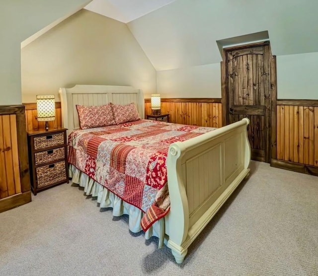 bedroom featuring light carpet, a wainscoted wall, lofted ceiling, and wood walls