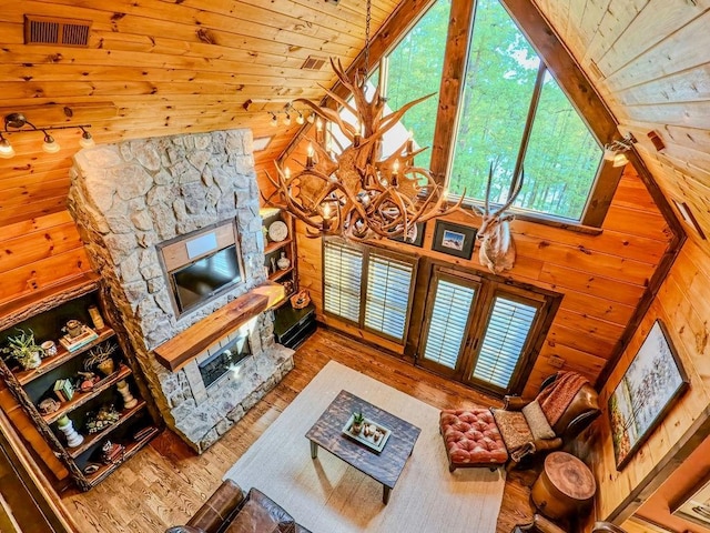 living area featuring a fireplace, wood walls, wood finished floors, wood ceiling, and high vaulted ceiling