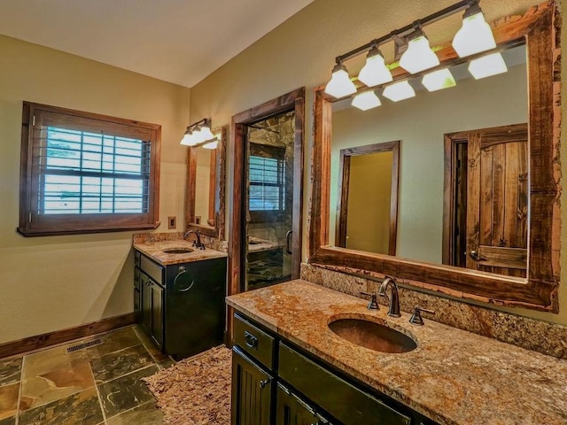 bathroom with stone finish floors, two vanities, and baseboards