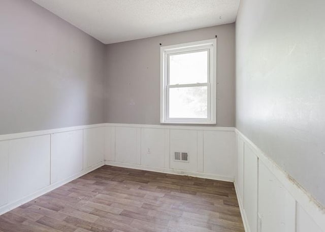4709 Mcdonald Ave, West Columbia, SC 29172 - unfurnished room featuring wainscoting, a decorative wall, wood finished floors, and a textured ceiling