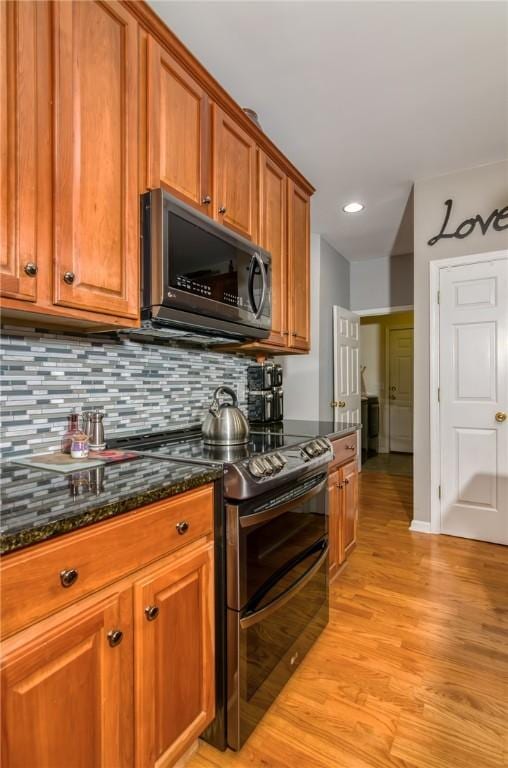 606 Greening Dr, Simpsonville, SC 29681 - kitchen featuring black microwave, double oven range, brown cabinetry, light wood-type flooring, and tasteful backsplash