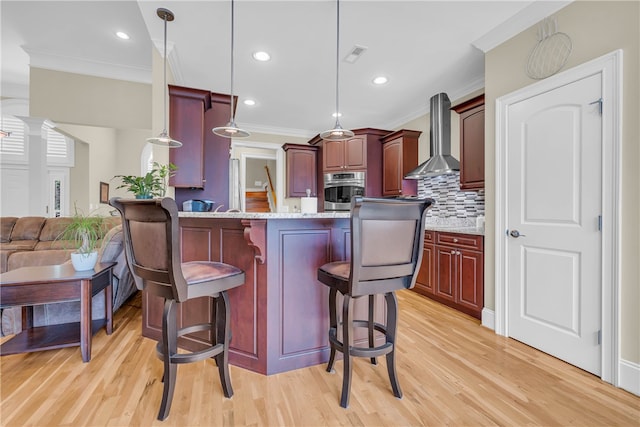 117 W Waters Edge Ln, West Union, SC 29696 - kitchen featuring oven, wall chimney range hood, light wood-type flooring, a breakfast bar area, and crown molding