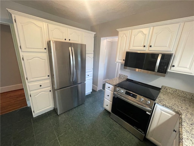 501 Seneca Dr, Seneca, SC 29678 - kitchen featuring stainless steel appliances, white cabinets, light stone counters, baseboards, and a textured ceiling