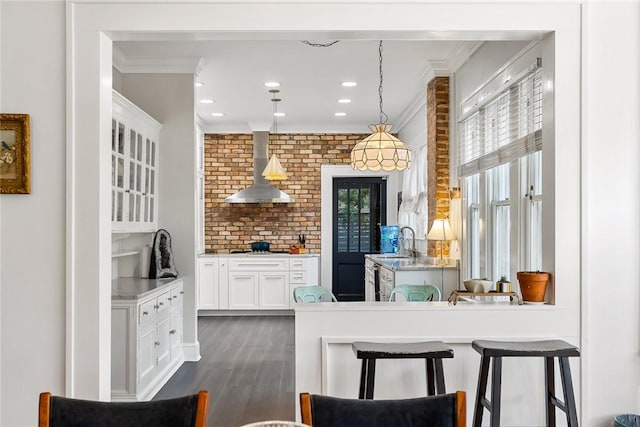 227 S Main St, Honea Path, SC 29654 - kitchen with wall chimney range hood, ornamental molding, a sink, white cabinetry, and dark wood-type flooring