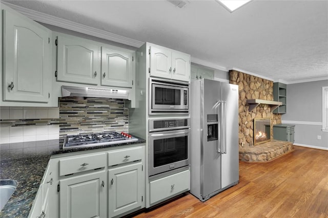 133 Cherokee Rd, Easley, SC 29642 - kitchen with appliances with stainless steel finishes, a fireplace, ornamental molding, decorative backsplash, and light wood-type flooring
