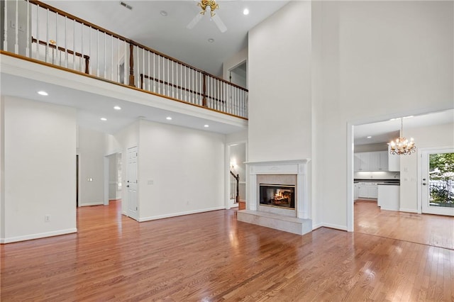 118 Pinnacle Pointe Dr, Seneca, SC 29672 - unfurnished living room featuring a high ceiling, a premium fireplace, light wood finished floors, ceiling fan, and a chandelier