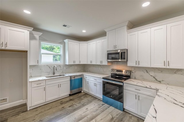 107A Avondale Rd, Anderson, SC 29624 - kitchen featuring appliances with stainless steel finishes, a sink, white cabinetry, light wood-type flooring, and backsplash