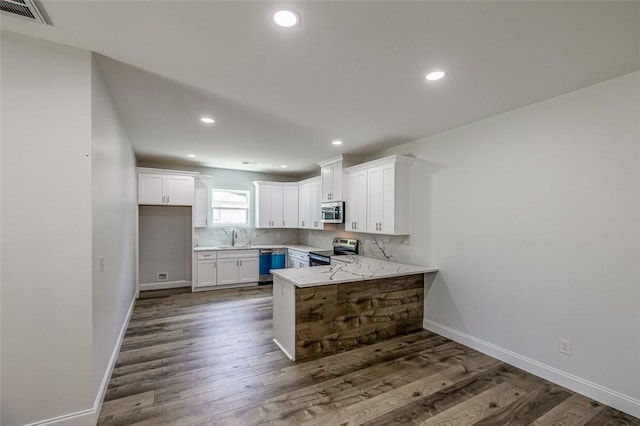 107A Avondale Rd, Anderson, SC 29624 - kitchen with appliances with stainless steel finishes, a peninsula, white cabinetry, dark wood-style flooring, and backsplash