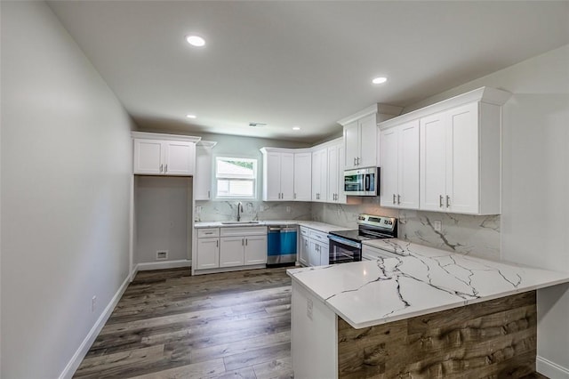107A Avondale Rd, Anderson, SC 29624 - kitchen with stainless steel appliances, white cabinets, a peninsula, wood finished floors, and tasteful backsplash