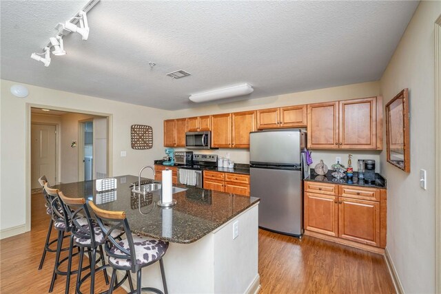 1523 Gadwell Way, Seneca, SC 29678 - kitchen featuring stainless steel appliances, a sink, wood finished floors, a kitchen bar, and a textured ceiling