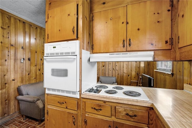 134 Grasshopper Hill Rd, Pickens, SC 29671 - kitchen with white appliances, under cabinet range hood, wooden walls, brown cabinets, and light countertops