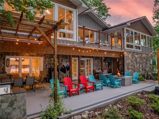 101 Westchester Cir, Seneca, SC 29672 - back of house at dusk featuring an outdoor fire pit, a wooden deck, stone siding, a pergola, and board and batten siding