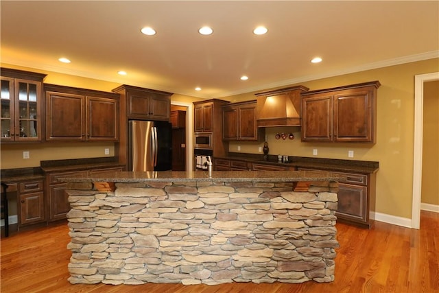 122 Langwell Dr, Anderson, SC 29621 - kitchen featuring stainless steel appliances, custom exhaust hood, an island with sink, ornamental molding, and glass insert cabinets