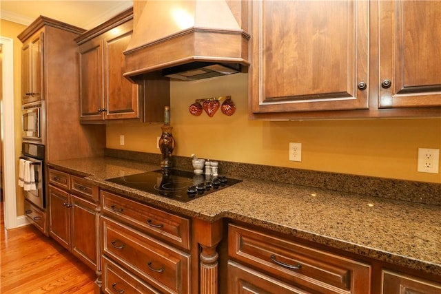 122 Langwell Dr, Anderson, SC 29621 - kitchen featuring stainless steel appliances, custom range hood, dark stone counters, and light wood-style floors