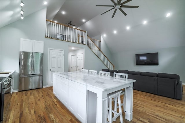 425 Lakewood Dr, Townville, SC 29689 - kitchen featuring appliances with stainless steel finishes, a ceiling fan, high vaulted ceiling, a kitchen breakfast bar, and white cabinetry
